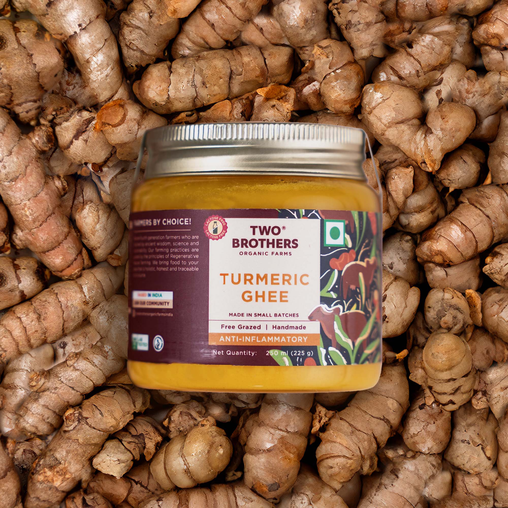A glass jar of anti-inflammatory turmeric ghee placed on top of a bed of raw turmeric roots