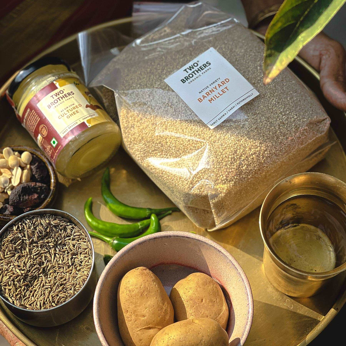 Healthy barnyard millet recipe preparation featuring a Two Brothers millet pack, organic ghee, and fresh spices for a nutritious meal.
