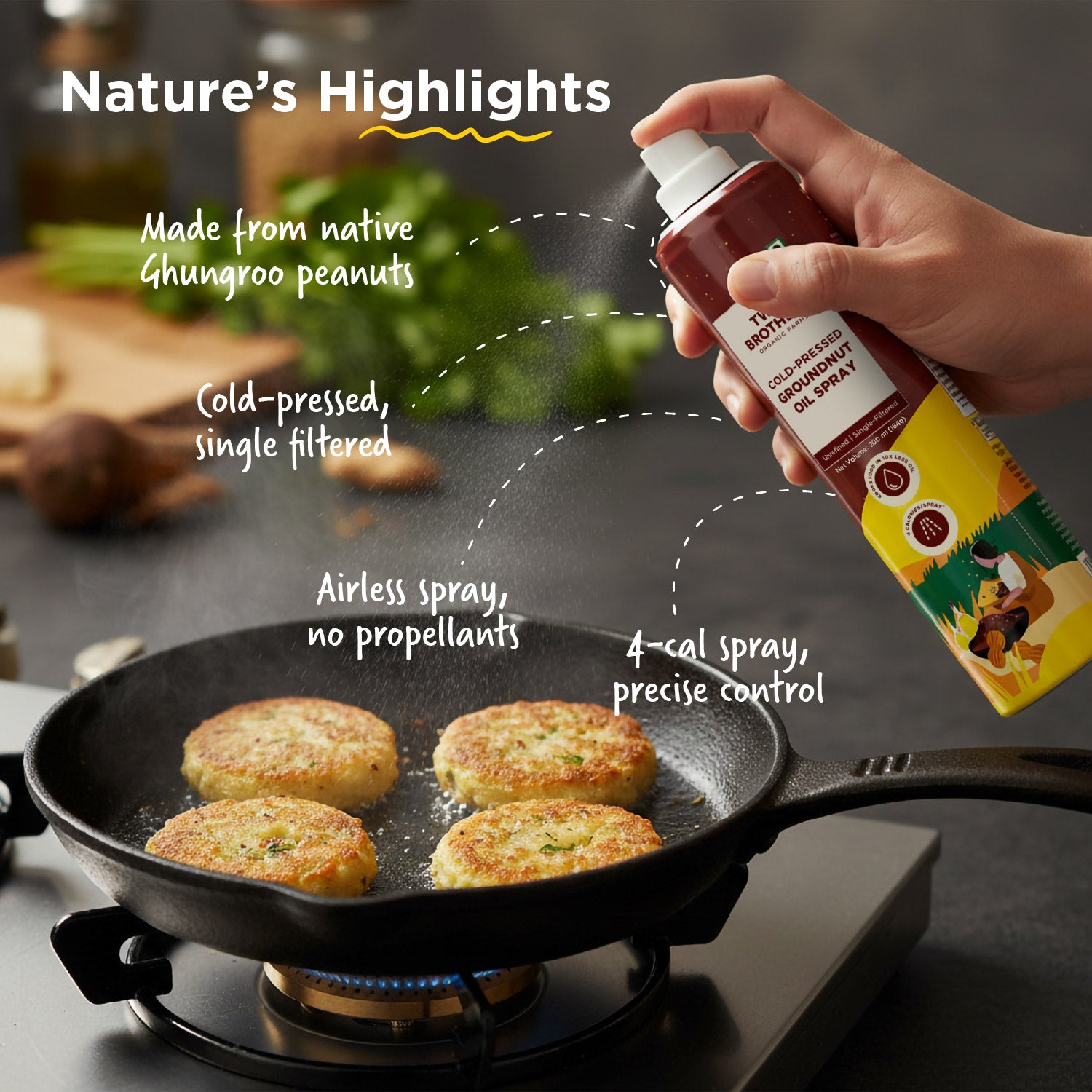 A hand spraying Two Brothers Ghungroo peanut oil into a pan, showcasing its airless propellant-free cooking spray design.